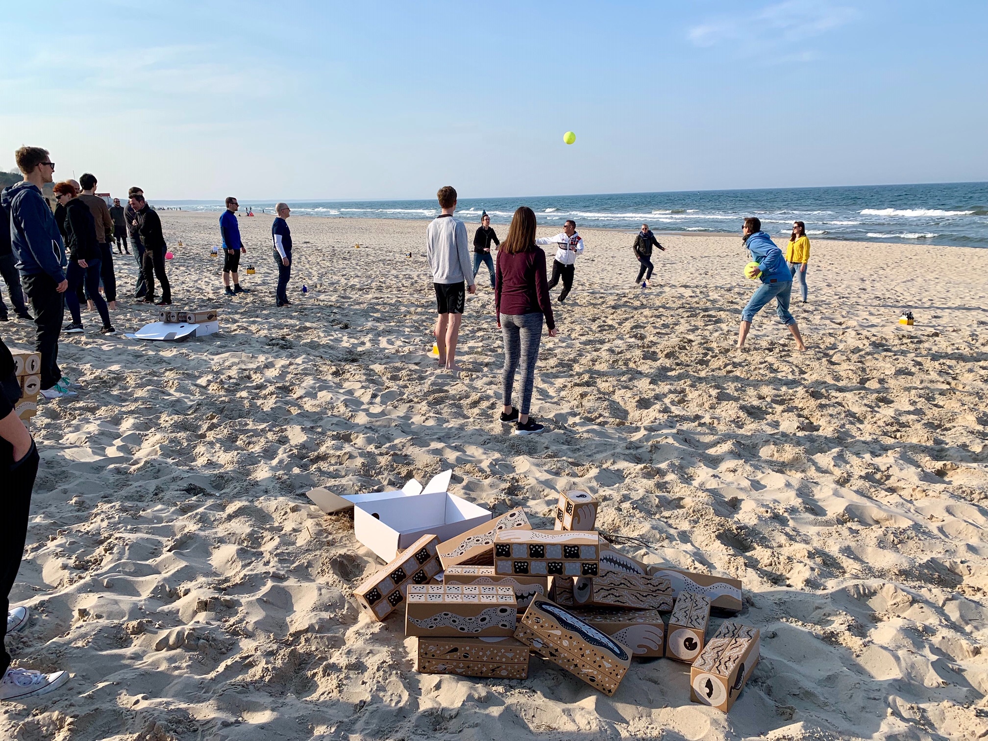 Menschen spielen Völkerball am Strand mit Kartons im Vordergrund